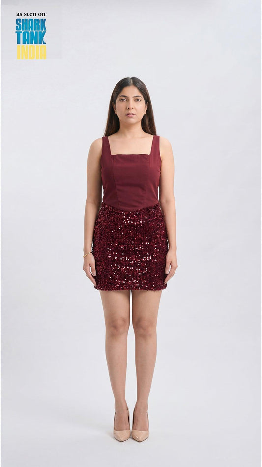 Woman wearing a burgundy dress with a sequin skirt on a white background