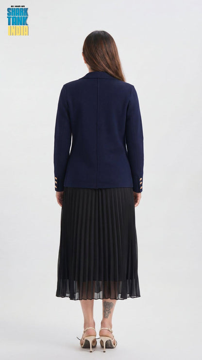 Woman wearing a navy blue cardigan and black pleated skirt on a white background
