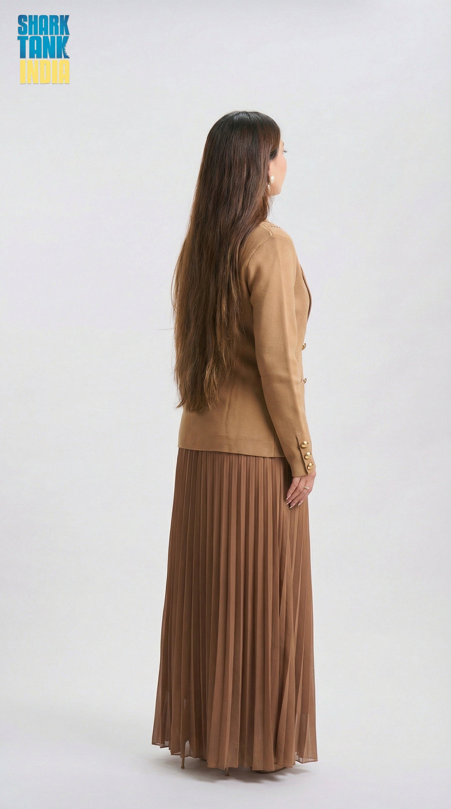 Woman wearing a brown outfit with a pleated skirt on a white background