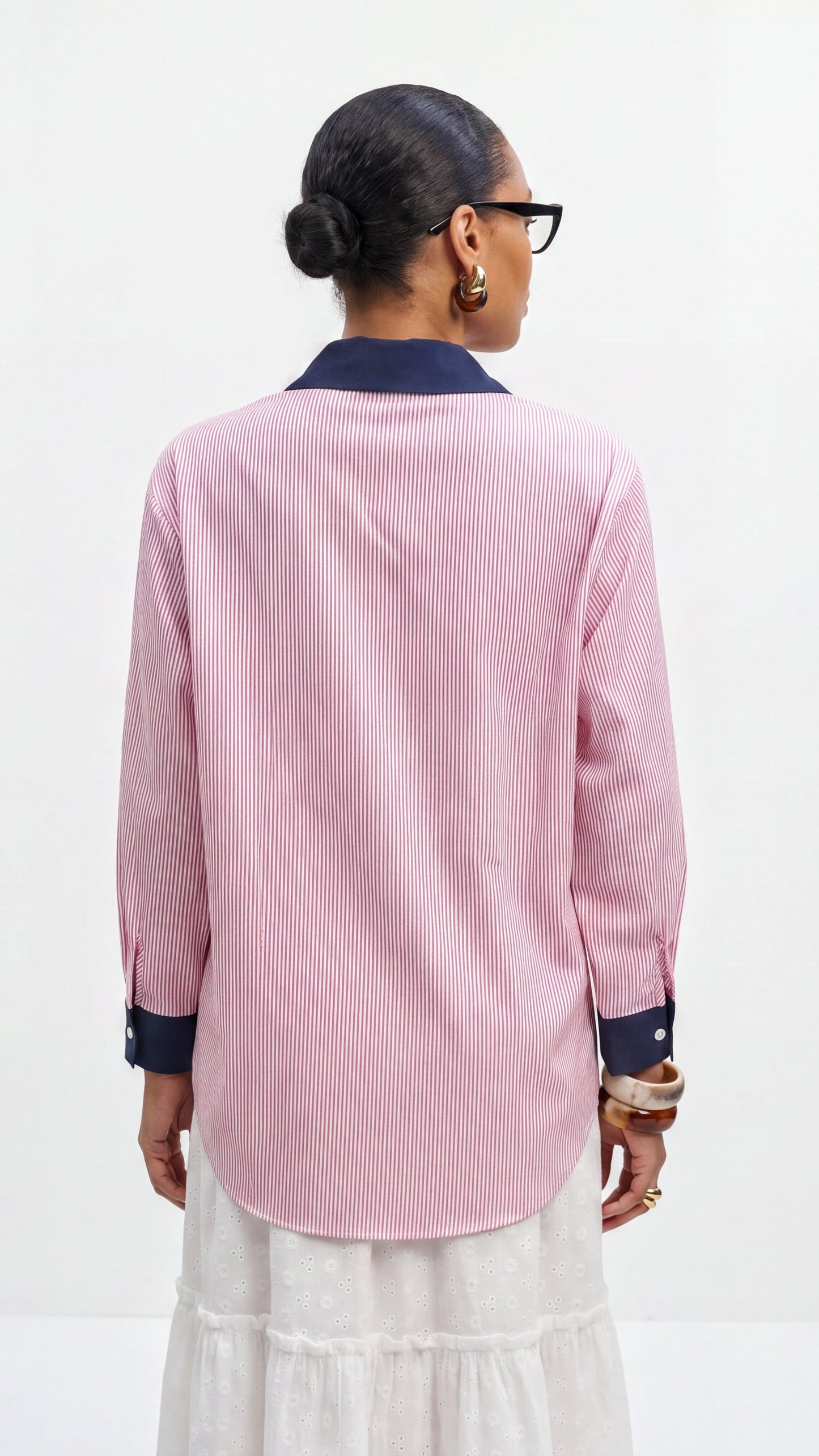 Person wearing a pink striped shirt with navy accents on a white background