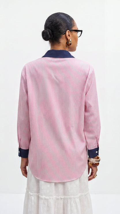 Person wearing a pink striped shirt with navy accents on a white background