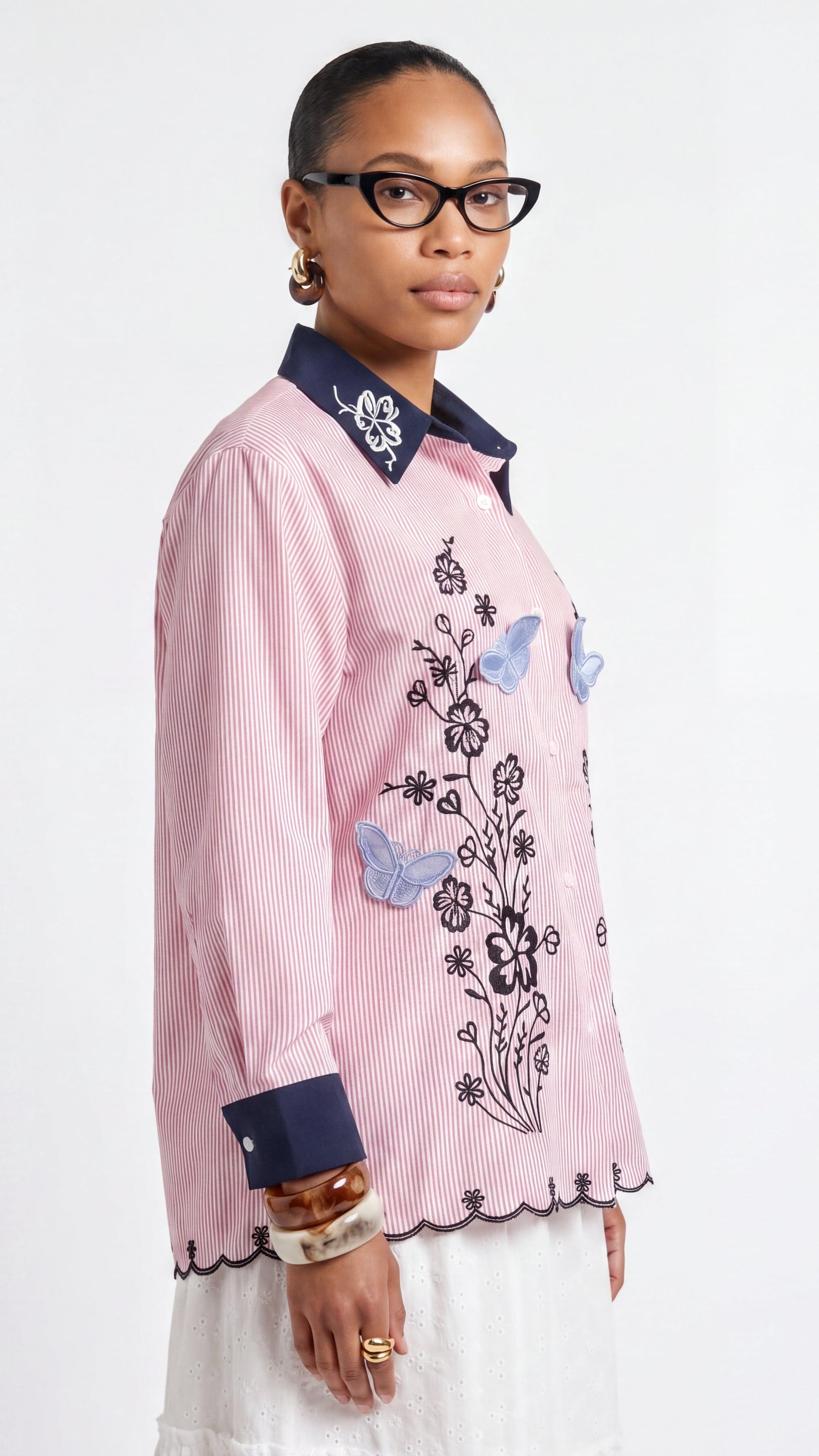 Woman wearing a pink blouse with floral and butterfly designs on a white background
