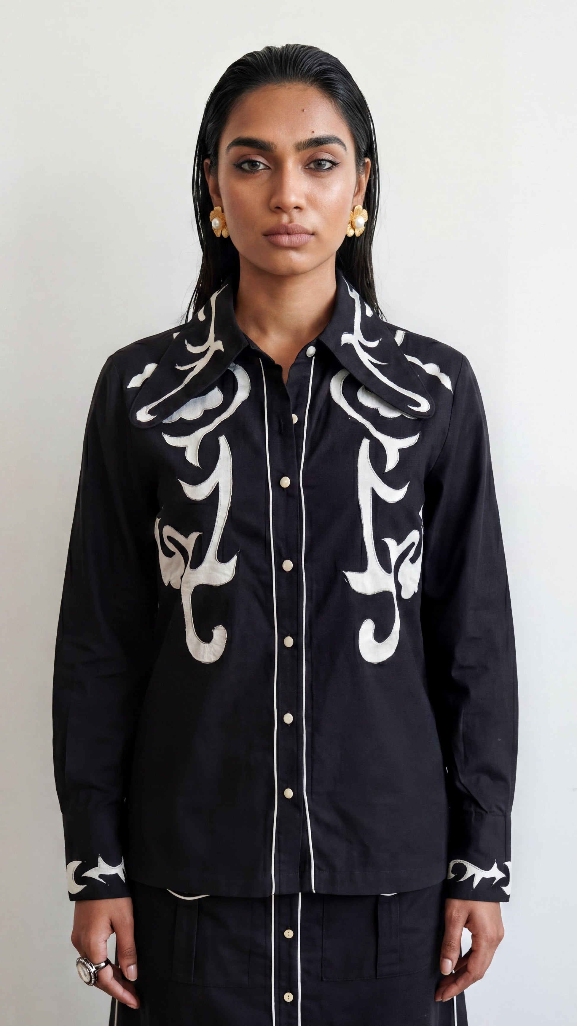 Person wearing a black shirt with white patterns on a plain background