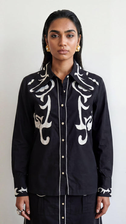 Person wearing a black shirt with white patterns on a plain background