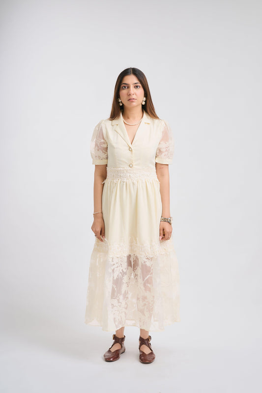 Woman wearing a cream-colored dress with sheer sleeves on a white background