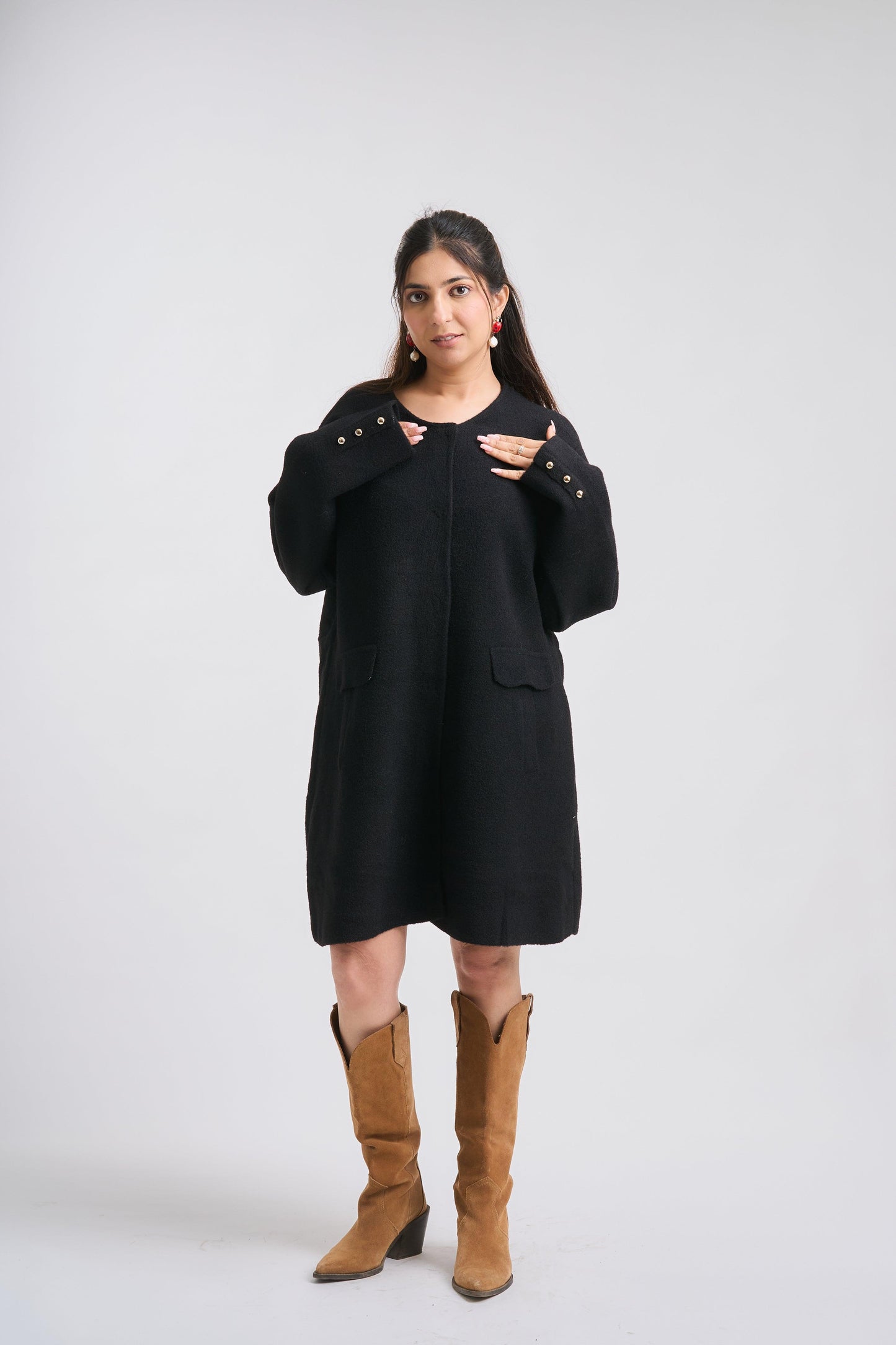 Woman wearing a black dress with brown boots on a white background