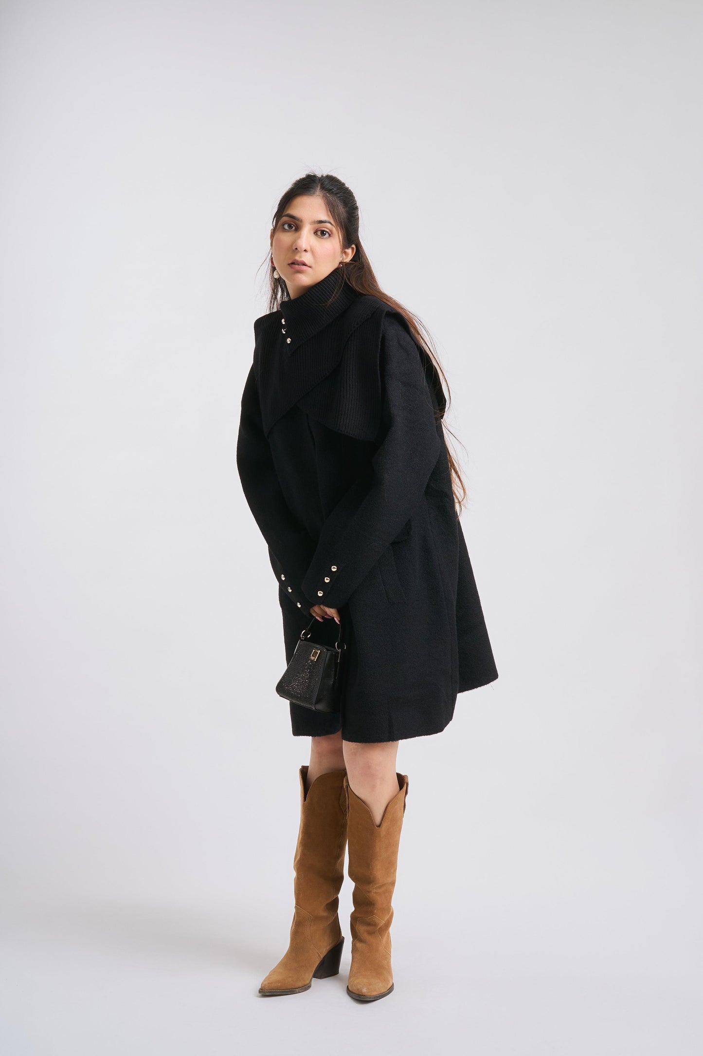 Woman wearing a black coat and brown boots on a white background