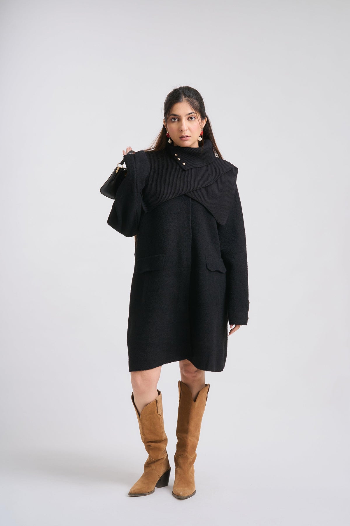 Woman wearing a black coat and brown boots on a white background