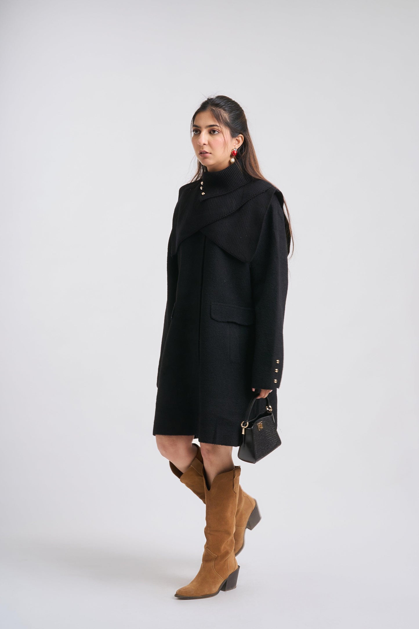 Woman wearing a black coat and brown boots on a white background