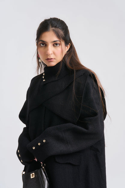 Woman wearing a black coat with gold buttons on a white background