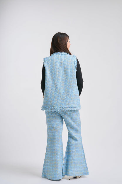 Person wearing a light blue textured vest and flared pants on a white background