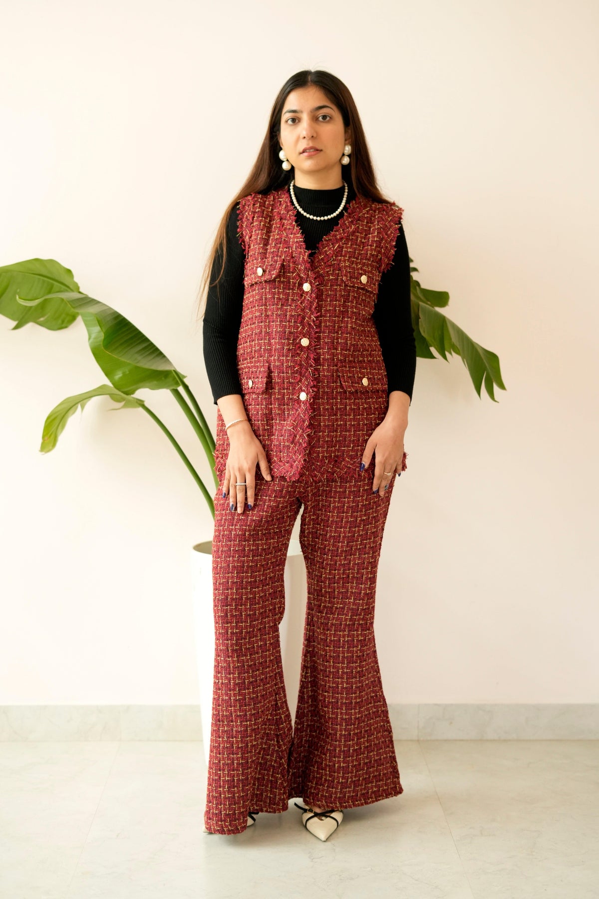 Woman wearing a red checkered jumpsuit with a vest against a white background