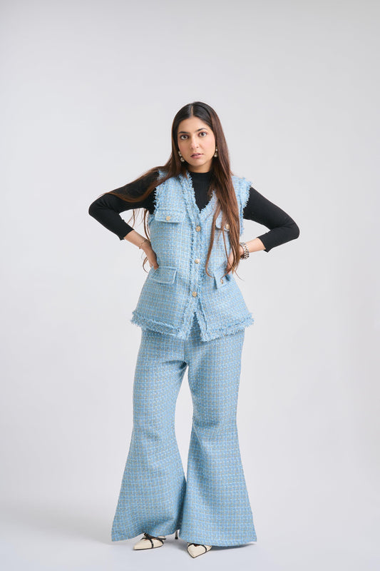 Woman wearing a light blue checkered outfit with a vest on a white background