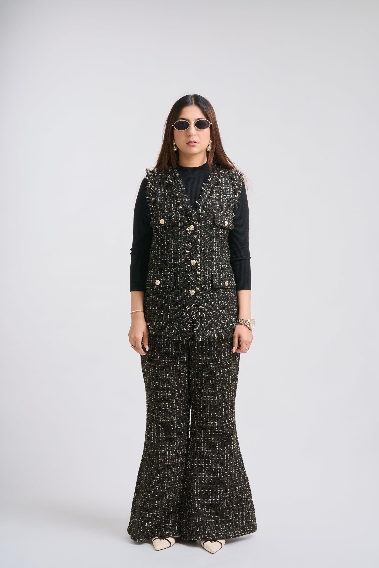 Person wearing a patterned vest and wide-leg pants on a white background