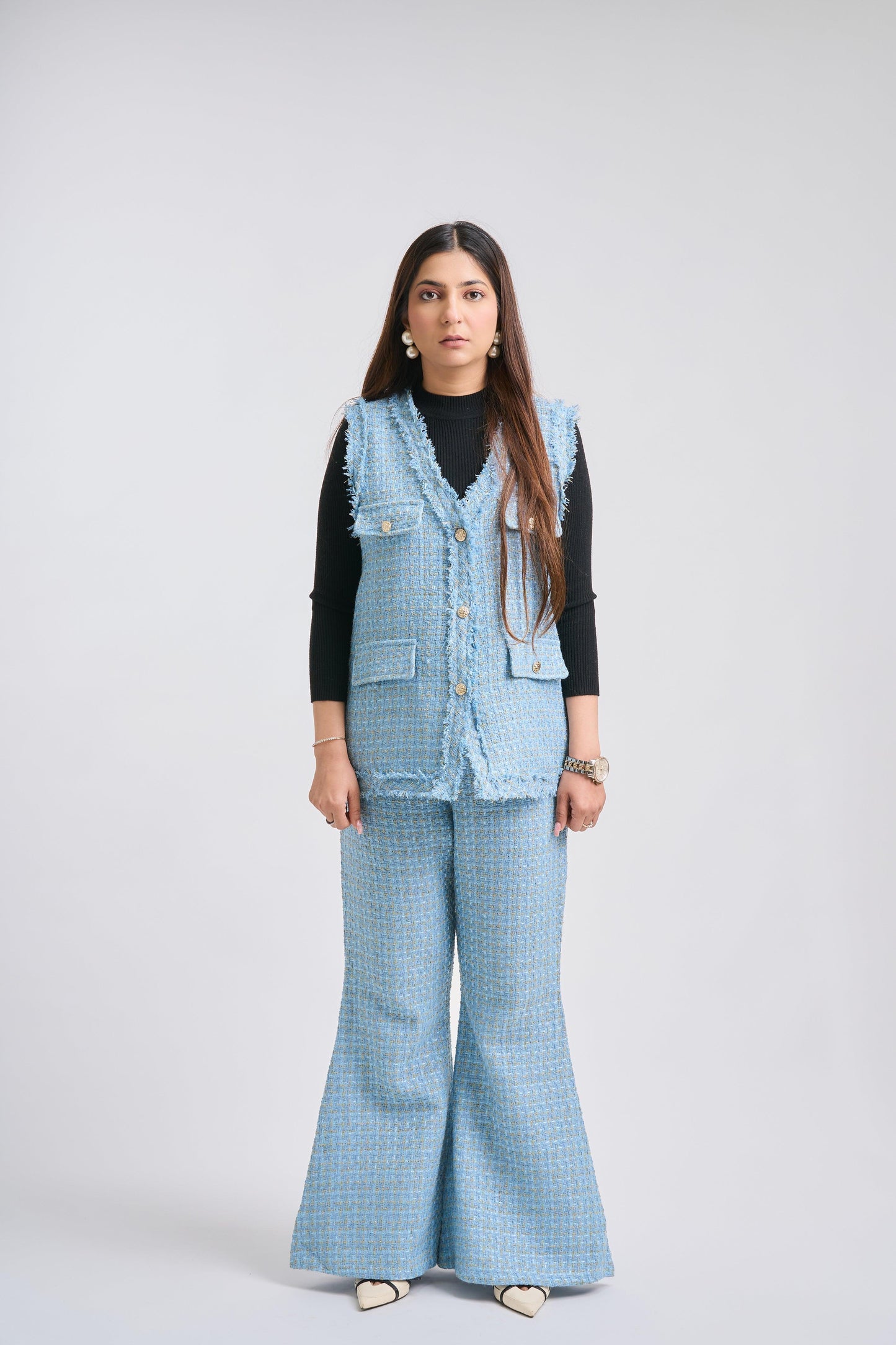 Woman wearing a blue checkered outfit with a vest on a white background