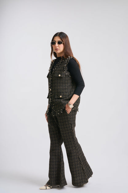 Woman wearing a black studded vest and flared pants on a white background