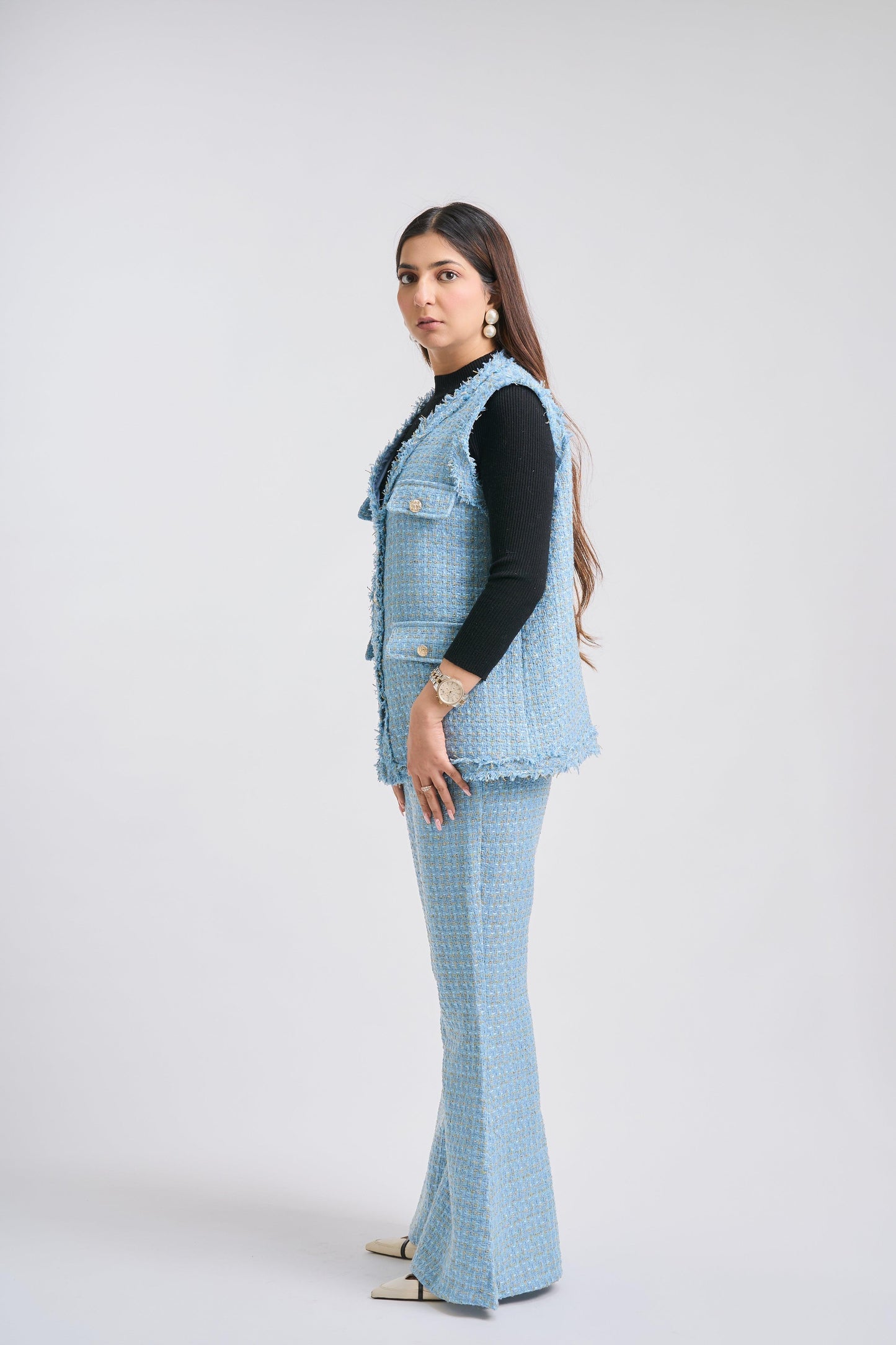 Woman wearing a light blue checkered outfit with a vest on a white background