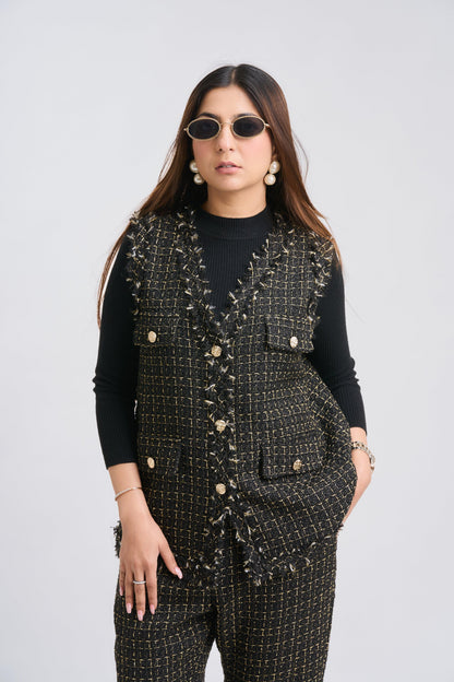 Woman wearing a black patterned vest over a black top on a white background