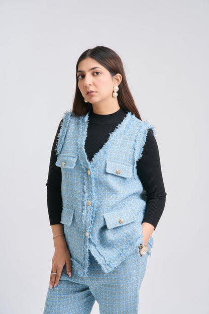 Woman wearing a light blue denim vest over a black top on a white background