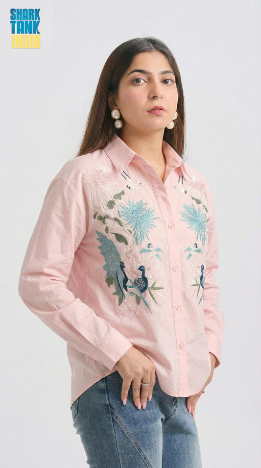Woman wearing a pink embroidered shirt with floral designs on a white background