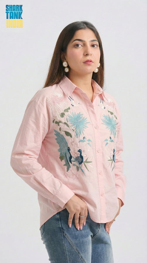 Woman wearing a pink embroidered shirt with floral designs on a white background