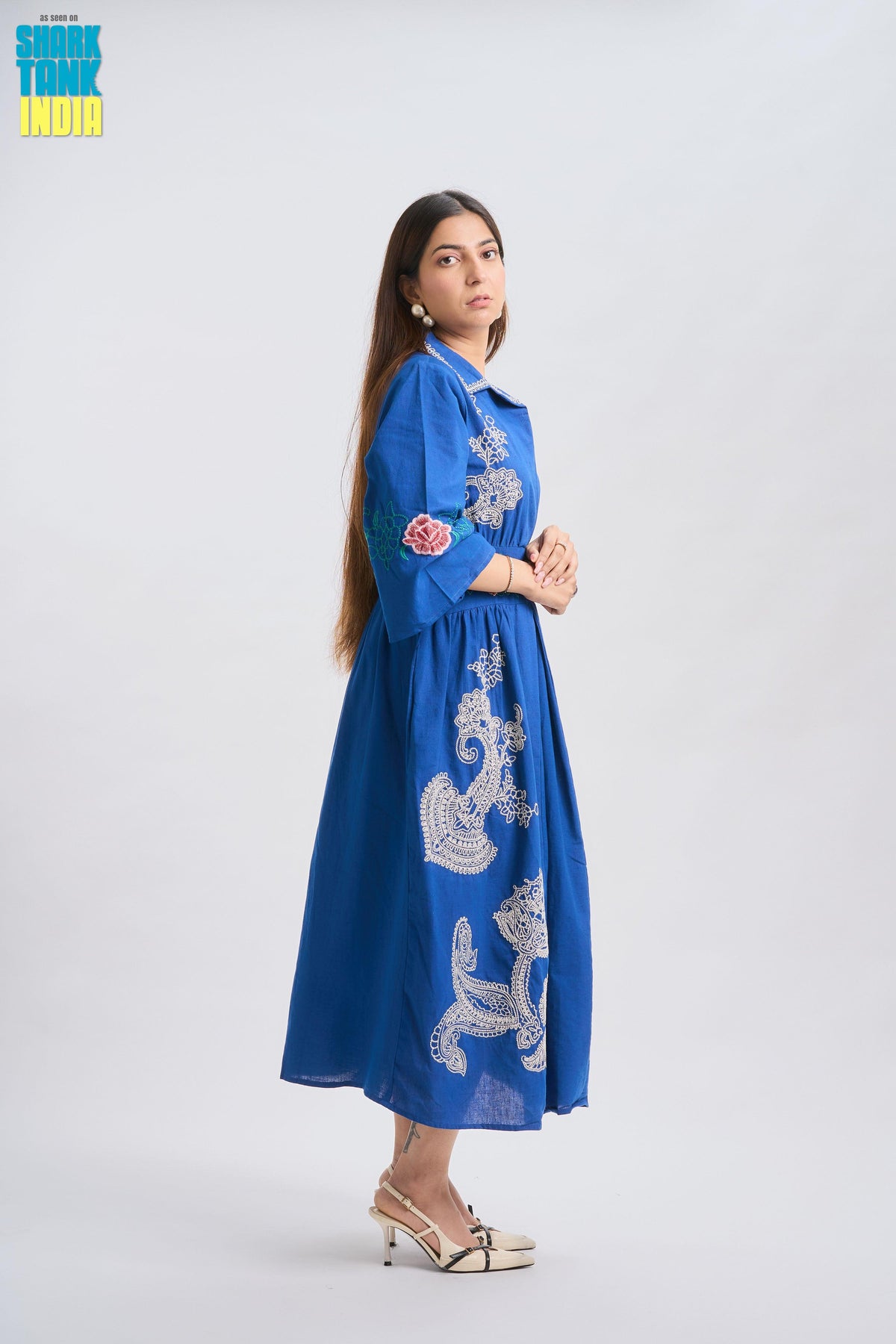 Woman wearing a blue embroidered dress on a white background