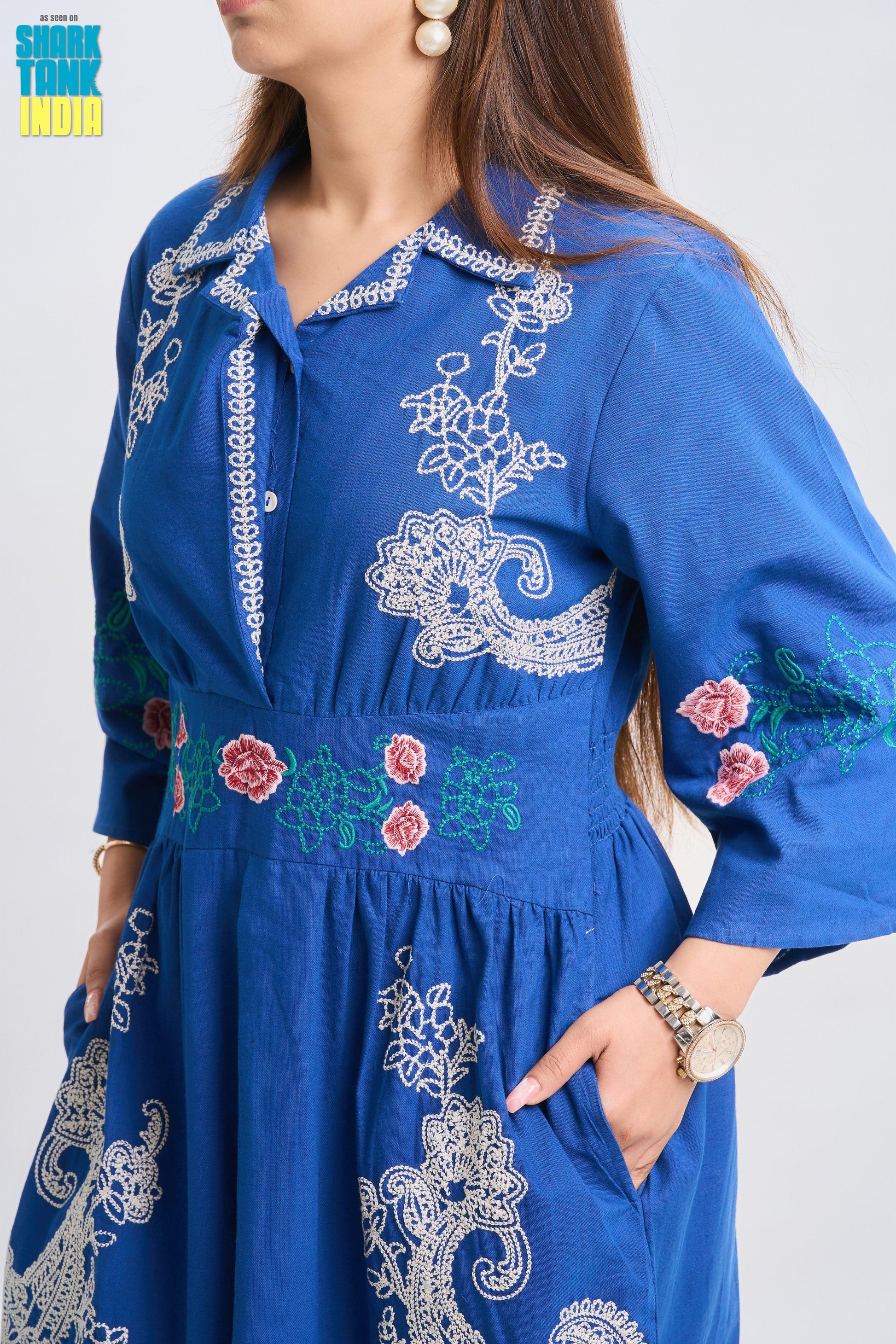 Blue embroidered dress worn by a person on a white background
