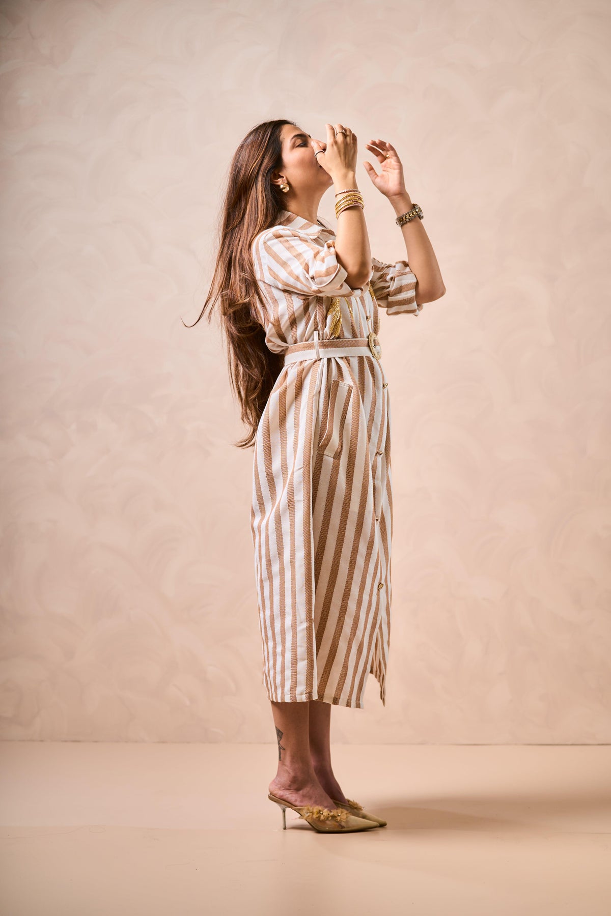 Woman wearing a striped dress against a beige background