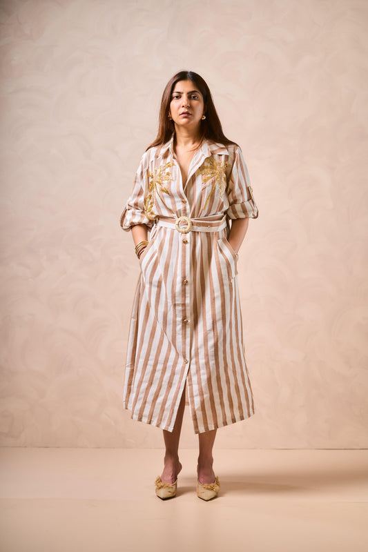 Woman wearing a striped dress with a belt against a beige background