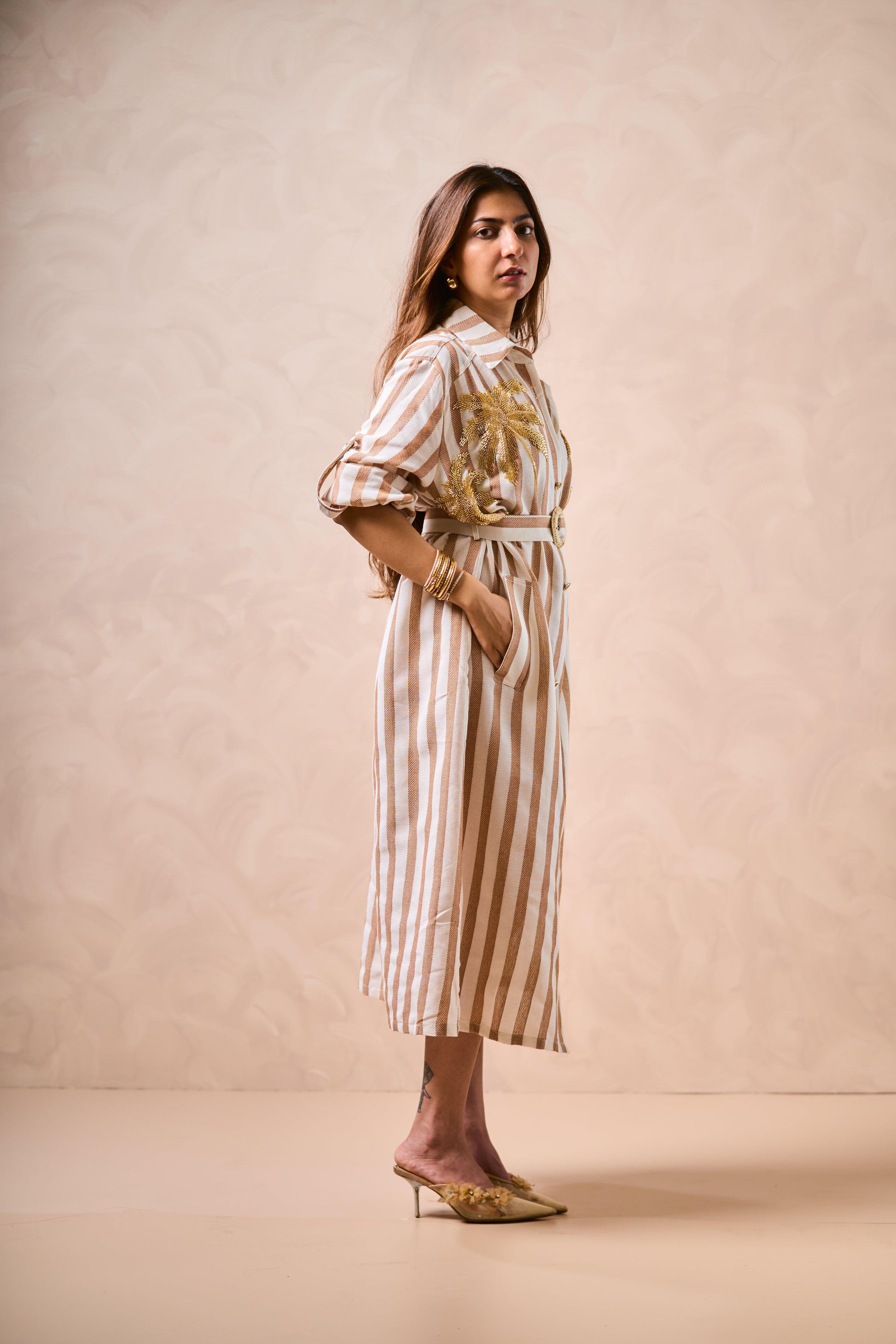 Woman wearing a striped dress with a palm tree design on a beige background
