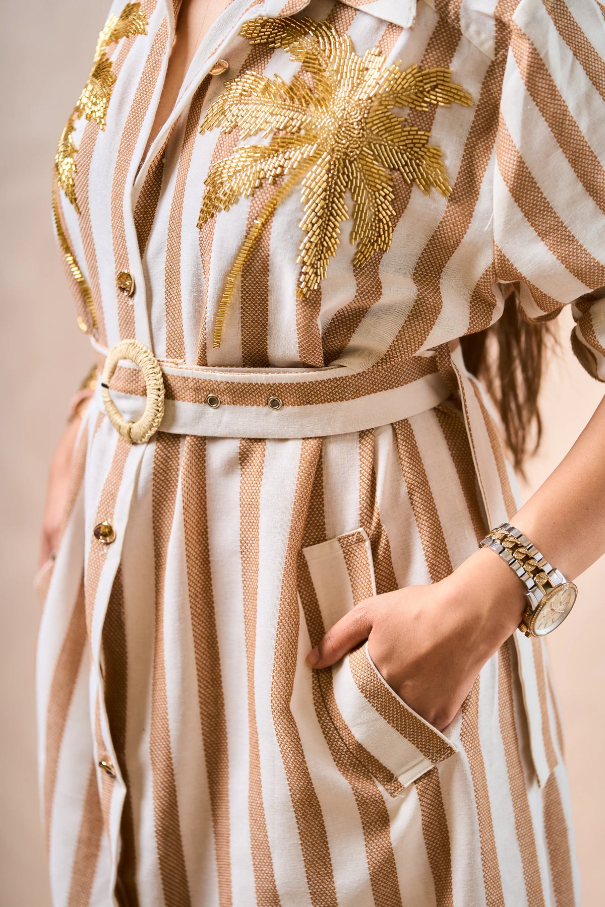 Striped dress with gold palm tree design and belt on a beige background