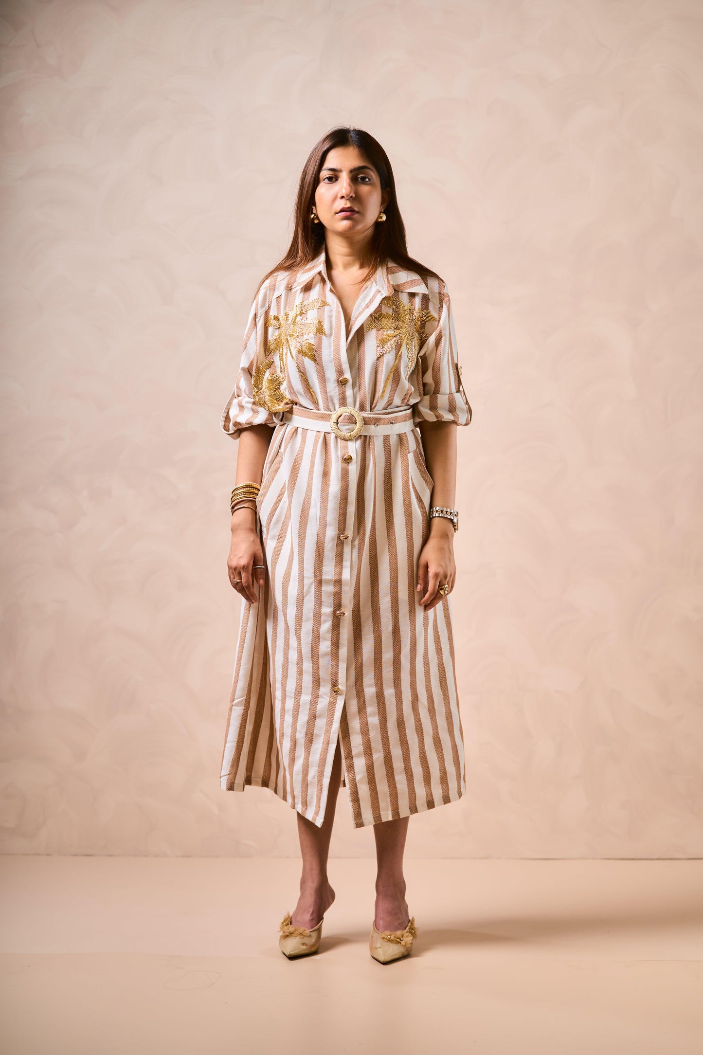 Woman wearing a striped dress with a belt against a beige background