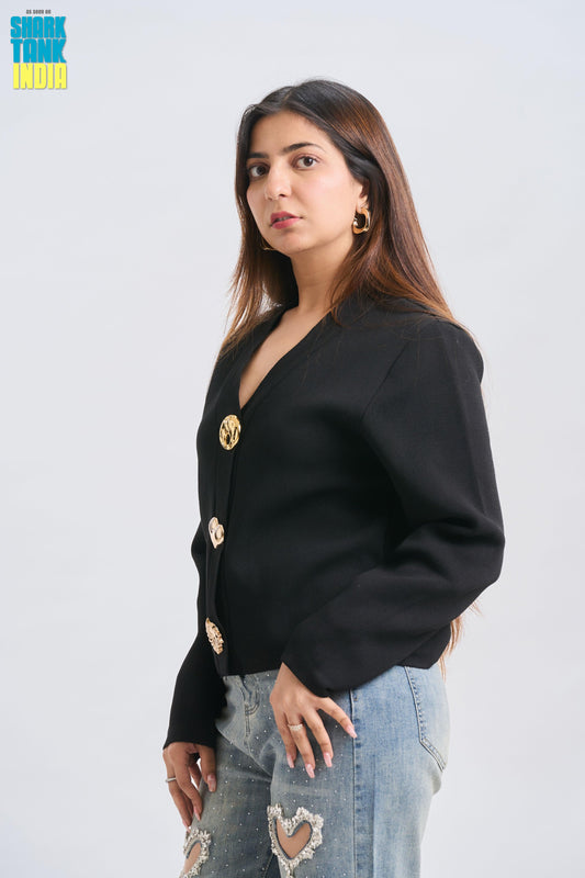 Woman wearing a black blazer with gold buttons on a light gray background