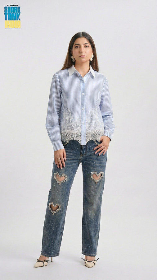 Woman wearing a blue and white striped shirt with lace details and distressed jeans on a white background.