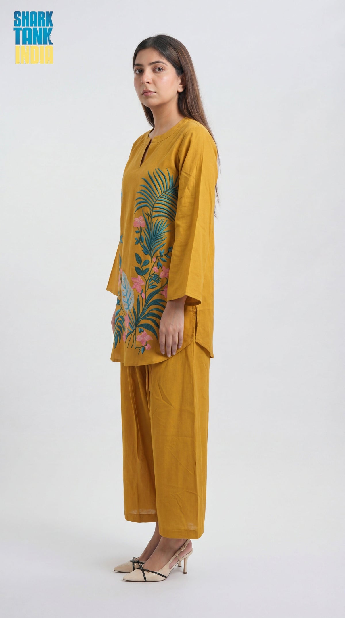 Woman wearing a mustard yellow outfit with floral design on a white background