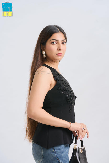 Woman wearing a black sleeveless top with bead details on a white background