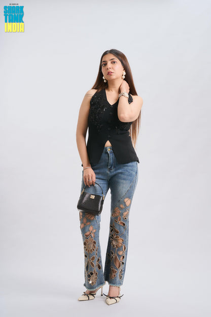 Woman wearing a black sleeveless top and blue jeans with floral patterns on a white background