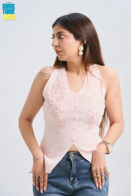 Woman wearing a light pink sleeveless top with buttons and blue jeans on a white background