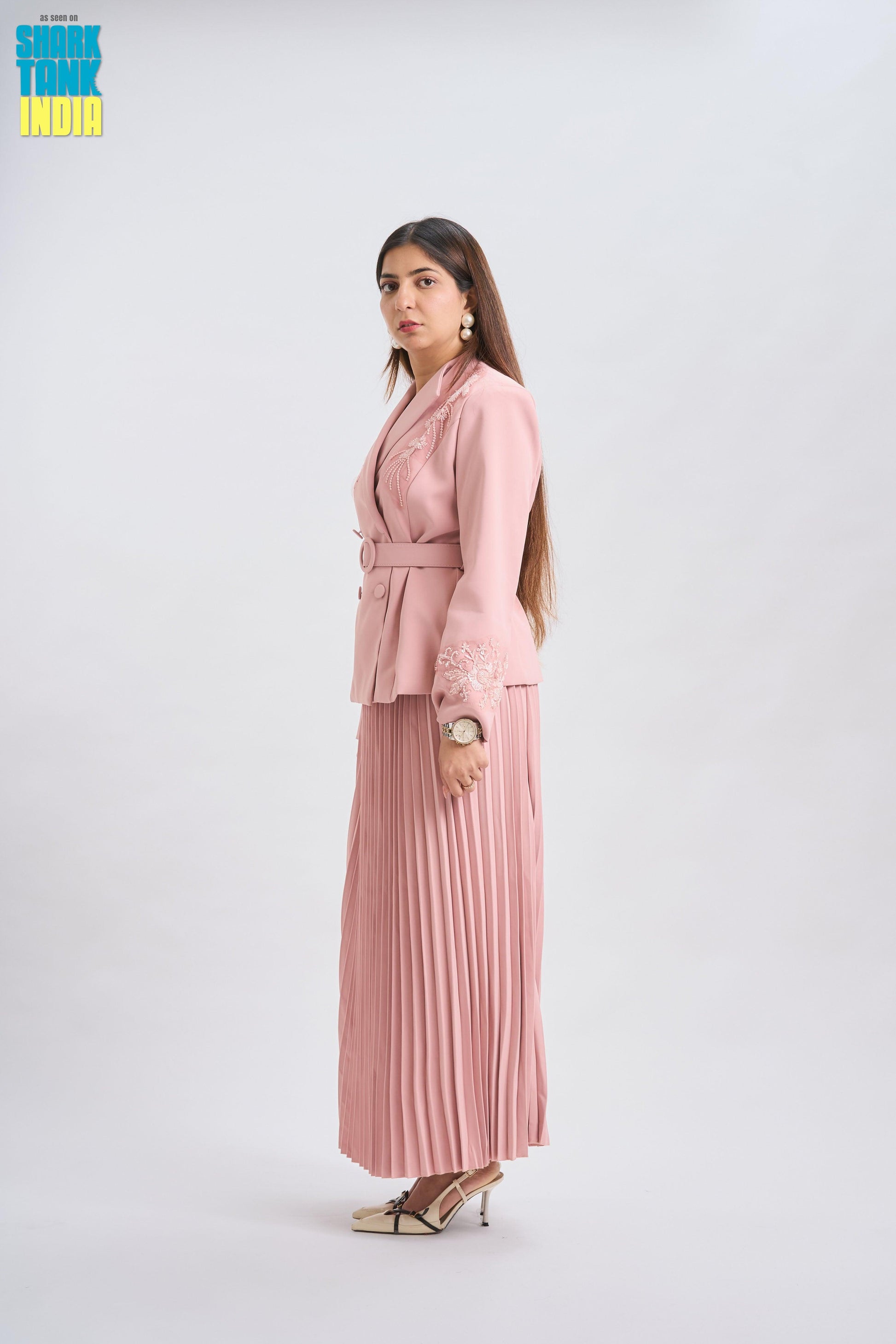 Woman wearing a pink outfit with a belt on a white background