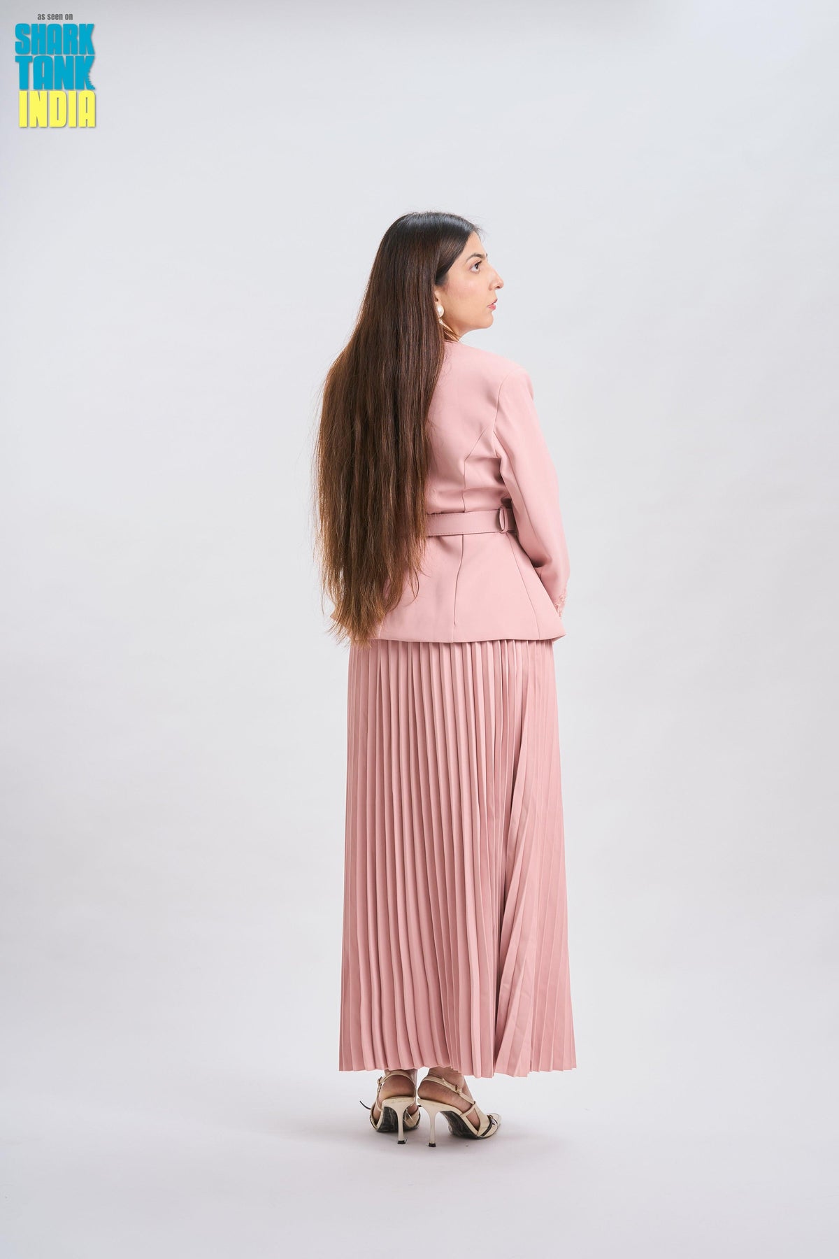 Woman in a pink outfit standing against a white background