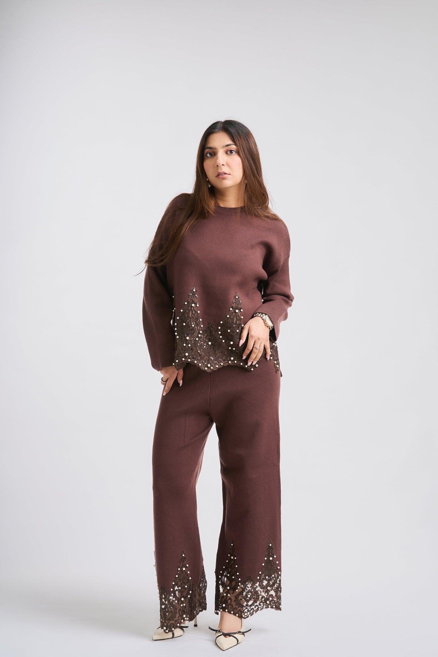 Woman wearing a brown outfit with embellishments on a white background