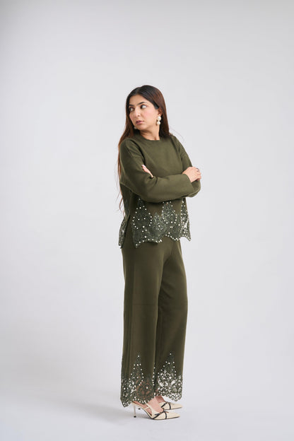 Woman wearing a green outfit with embellishments on a white background