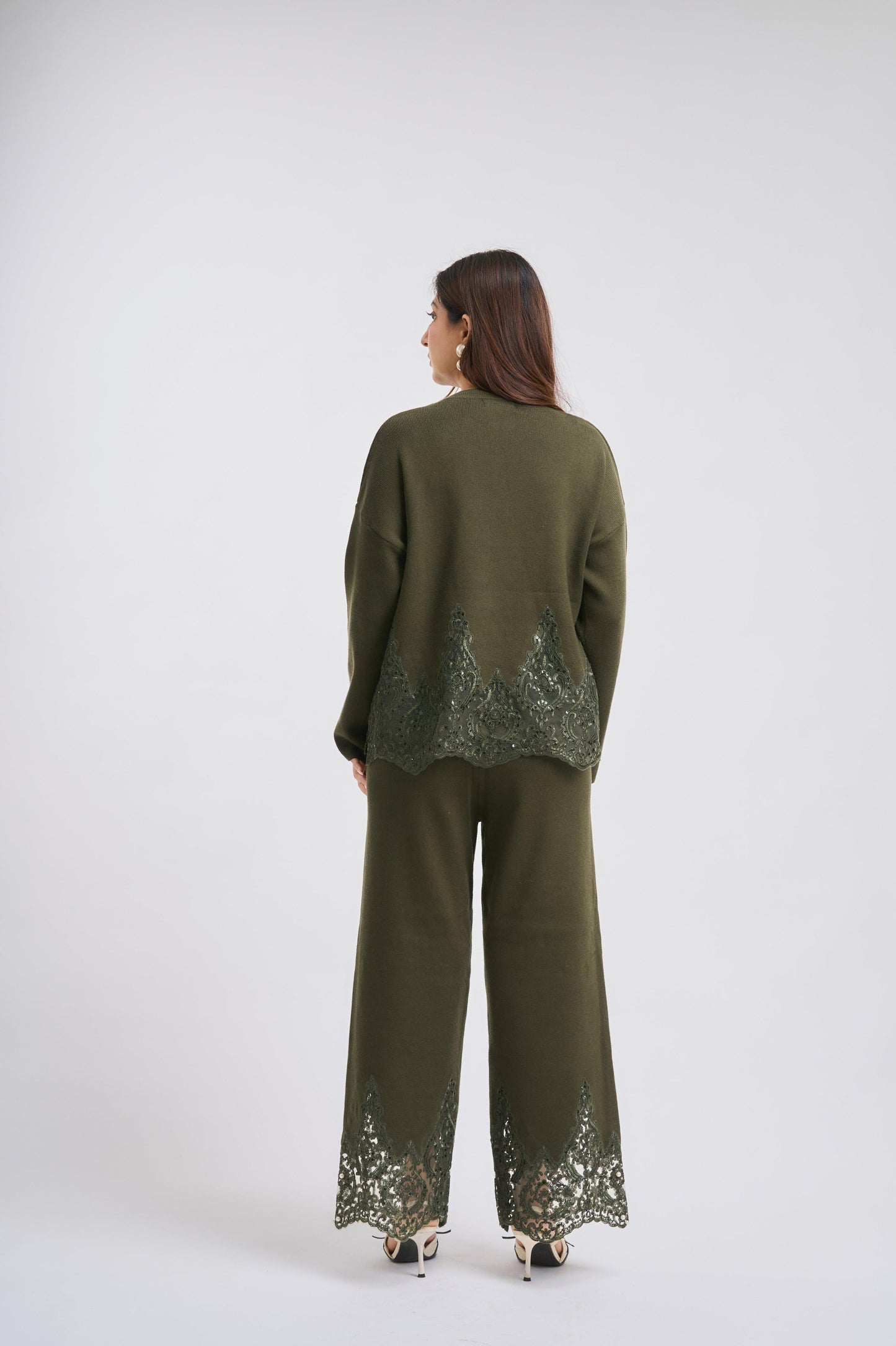 Woman wearing a green outfit with sequin details on a white background