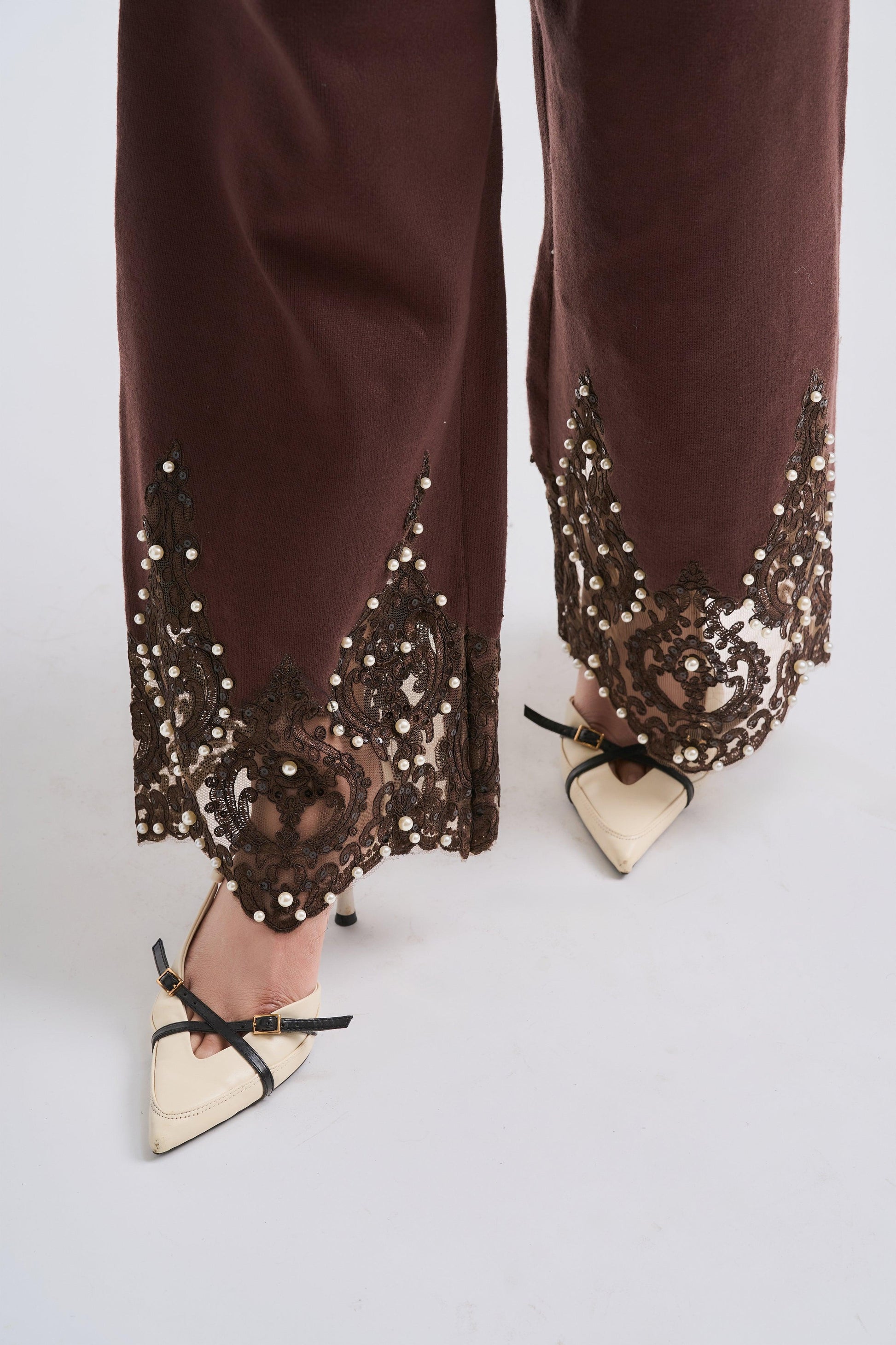 Brown pants with sequin detailing worn by a person on a white background