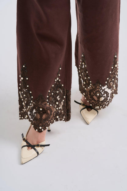 Brown pants with sequin detailing worn by a person on a white background