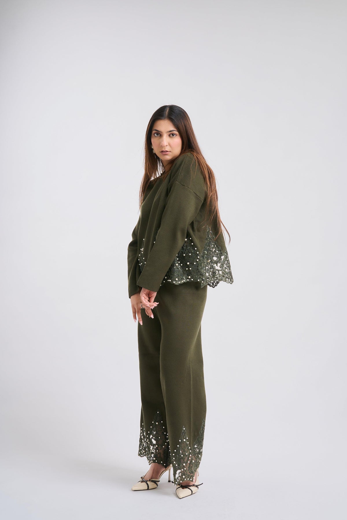 Woman wearing a green outfit with sequin details on a white background