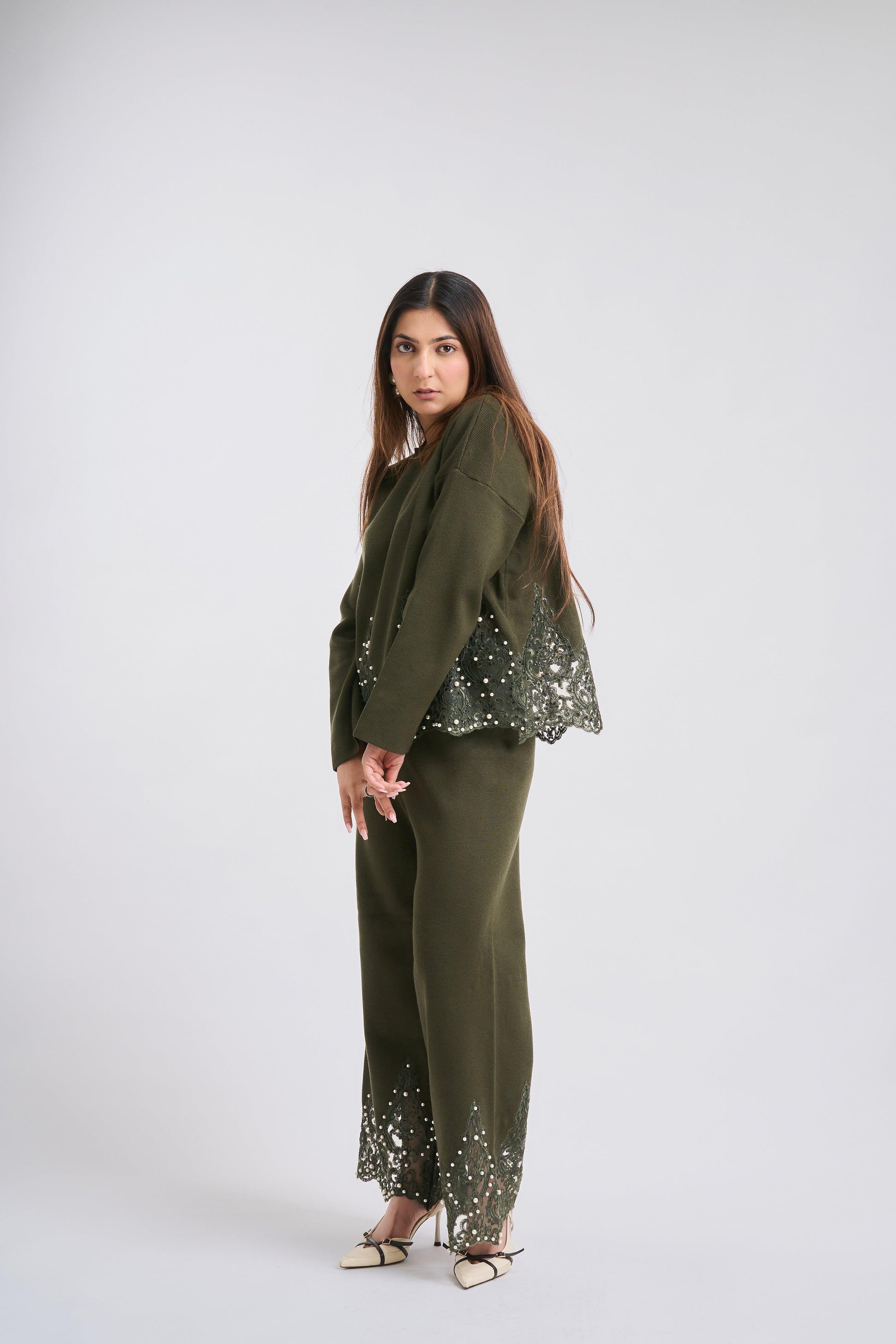 Woman wearing a green outfit with sequin details on a white background