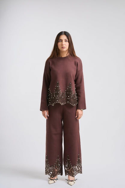 Woman wearing a brown outfit with embellishments on a white background