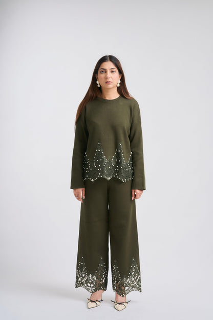 Woman wearing an olive green outfit with lace details on a white background
