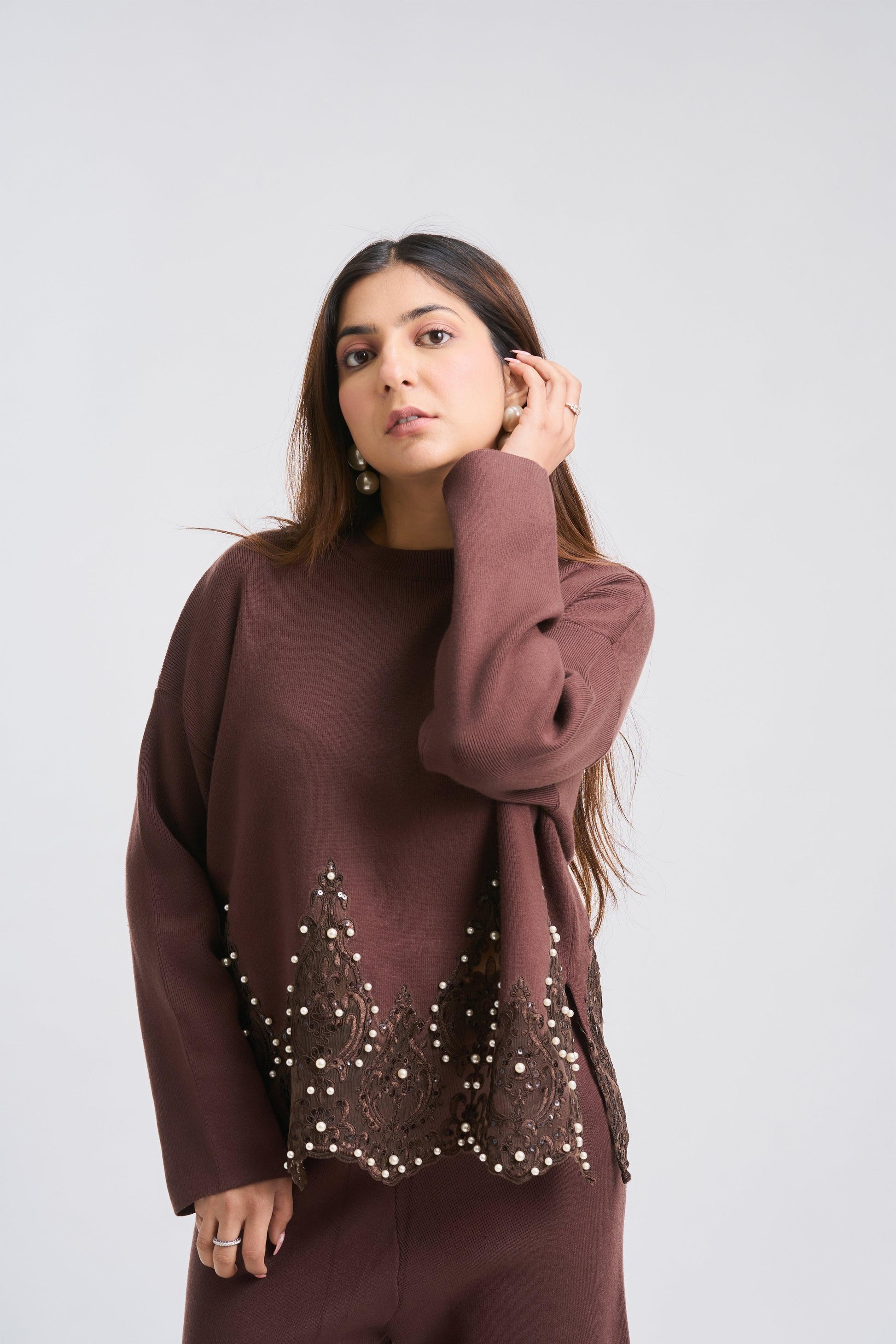 Woman wearing a brown outfit with intricate detailing on a white background